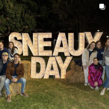 A group of people standing around a sign that reads "SNEAUX DAY"
