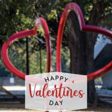 A photo of a modern art statue of two hearts with the caption "happy valentines day"