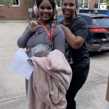 A girl and her mom posing to gether. The girl is putting up the UL handsign