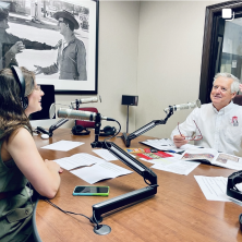 A man and a women doing a podcast together with microphones next to their faces