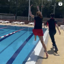 Two fully clothed orientation students jumping into a pool