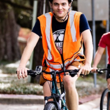A man wearing a orange safety vest on a bicycle