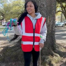 A girl in a red safety vest picking up trash