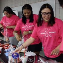 A group of students wearing pink Big Event shirts while doing service work
