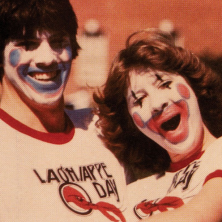 A vintage photo of two people wearing clown makeup and wearing Lagniappe Day shirts