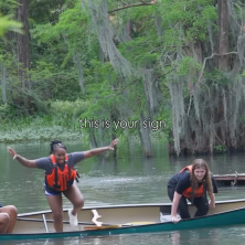 Two people jumping off of a canoe in the swamp