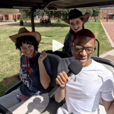 Three UL students drive around campus in a golf cart doing karaoke with a microphone 