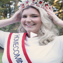 The UL Homecoming Queen places her crown on her head while smiling at the camera