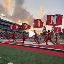 students run across the football field with ragin cajun flags