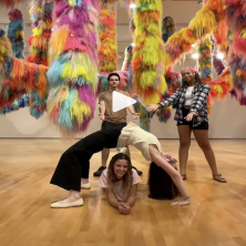 four students strike yoga poses in front of the X1 exhibition at the Hilliard Museum