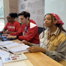 three students sit at a desk in the dupre library studying