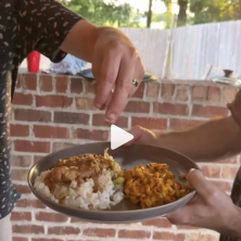 A man garnishes a plate of Louisiana cooking with green onions