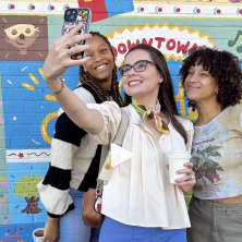 Three UL students take a selfie in front of the downtown mural