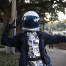 A UL student wearing an astronaut costume throws up the UL sign