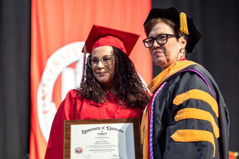 Sarah Beard crosses the stage in her cap and gown to collect her Health Services Administration degree