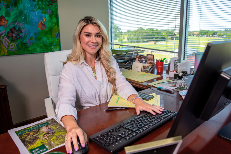 Graduate of the online MBA program works at her desk overlooking Moncus Park.