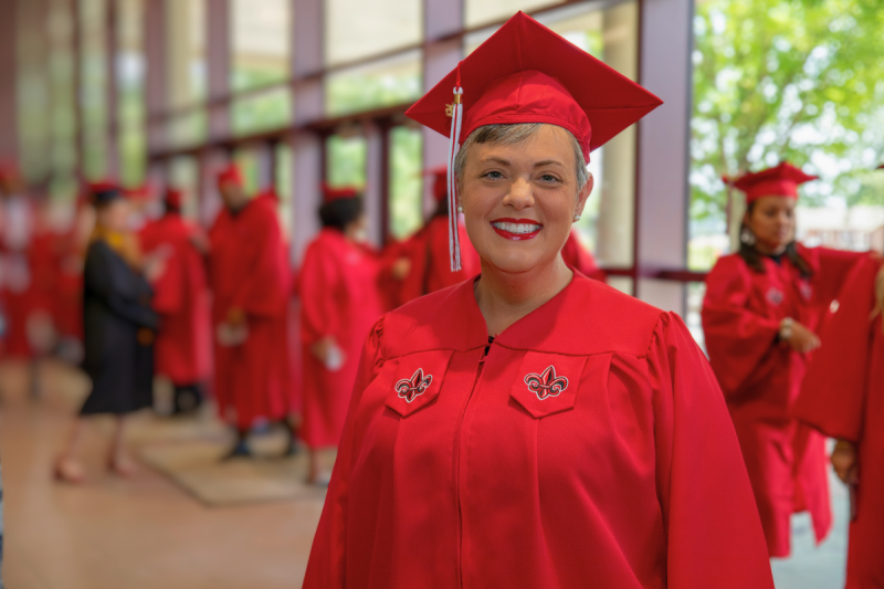Sommer Haas, alumna of UL Lafayette's online bachelor's program in general studies, smiles for a portrait in her cap and gown before graduation.