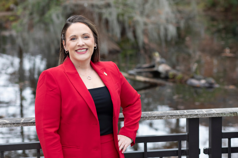 Amanda Devillier, alumna of UL Lafayette's MBA online, smiles for a portrait in front of Cypress Lake on campus.