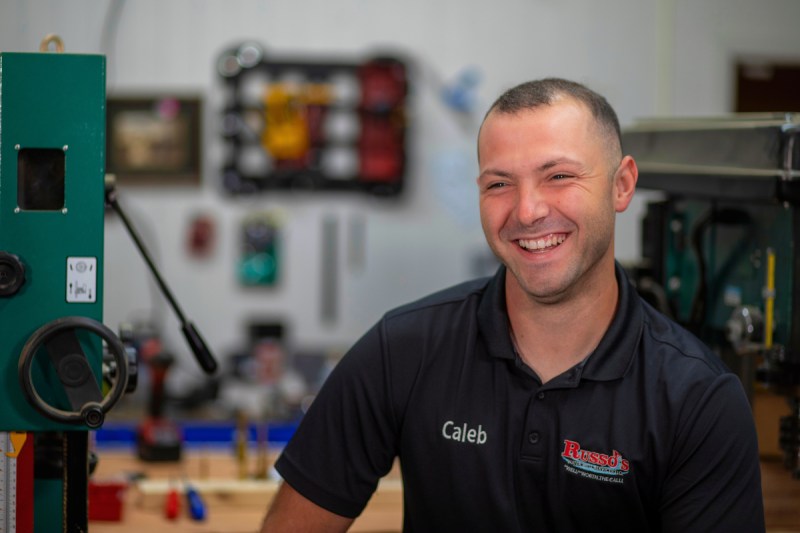 Engineering Technology online graduate Caleb Russo smiles wearing a black company polo. 