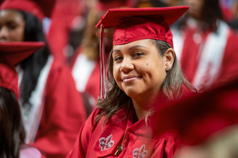 Online RN to BSN graduate smiles at graduation, wearing her red UL Lafayette cap and gown.