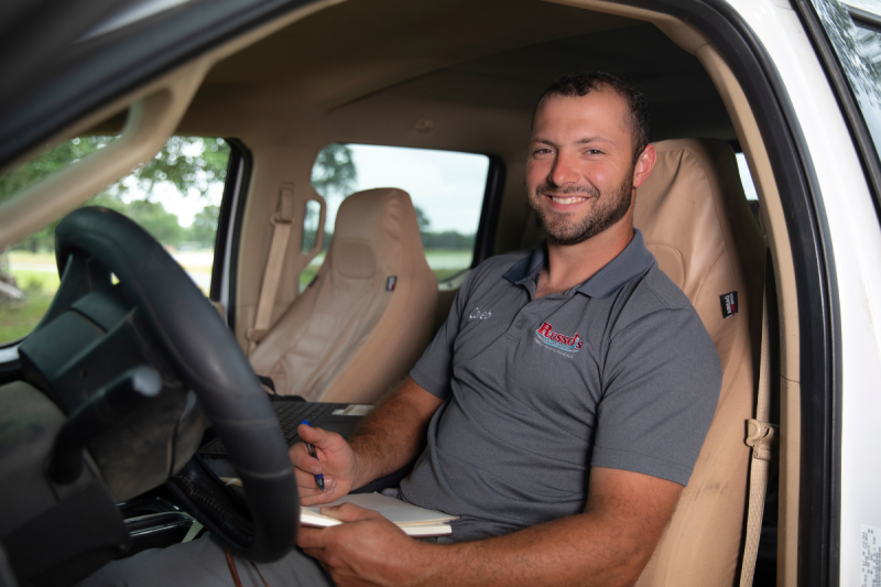 Engineering Management online grad smiles while doing schoolwork in his truck at the work site.