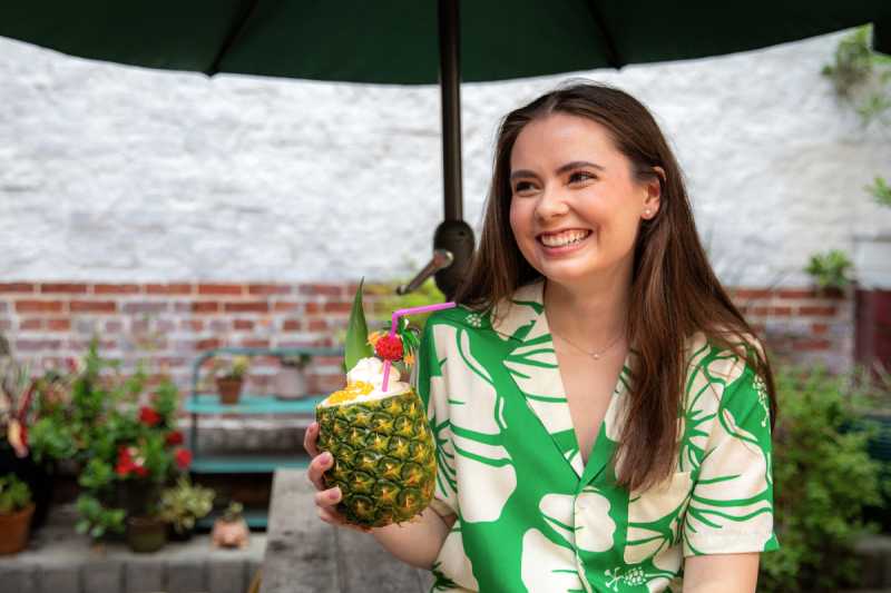 Alumna of UL Lafayette's psychology degree program smiles outside, wearing a green Hawaiian-print shirt.