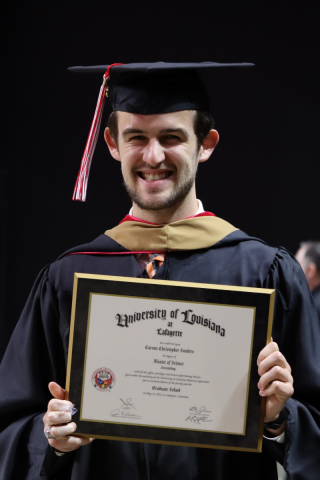 Carson Sanders holds up his degree during Spring 2022 commencement