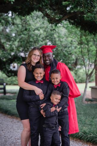 Tyrell Fenroy smiles with his wife and three sons. 