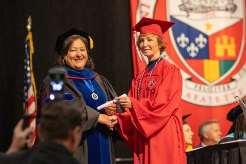 Lauren Lewis poses on the commencement stage with University College Dean Bobbie Decuir.