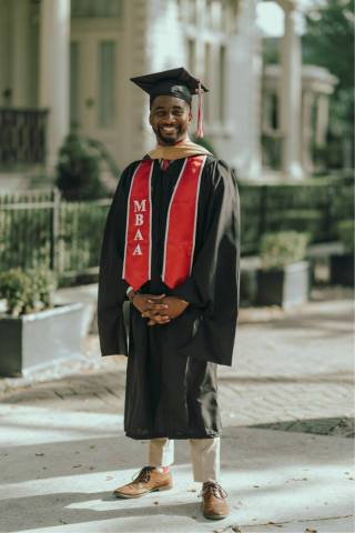 Ryan Owens, MBA, is pictured outside in his black and red UL Lafayette graduation cap and gown.