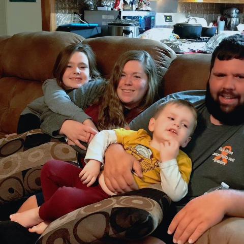 Zachary Badon is pictured with his wife and two children on a couch. Badon is earning his management degree online at UL Lafayette.