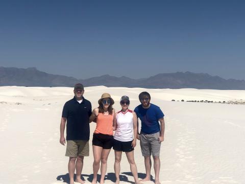 Erin Henry pictured with her husband, son, and daughter with sand and mountains in the background